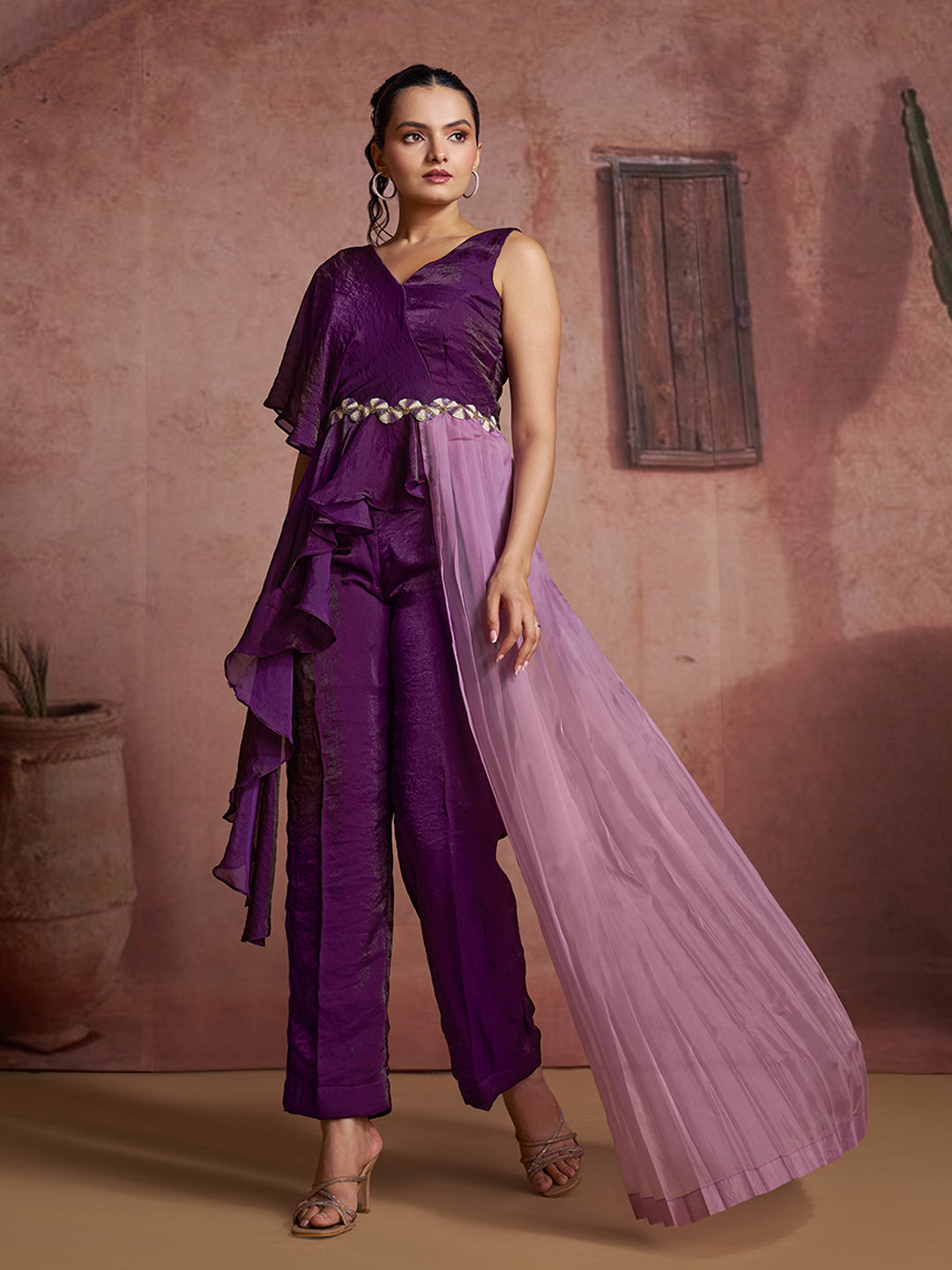 Elegant purple ruffled jumpsuit with a one-shoulder design and lavender pleated drape.